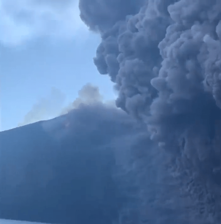  The volcano can be seen erupting in the background