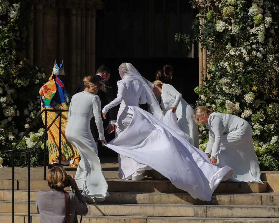 Ellie battled winds as she climbed the steps to her flower-adorned archway