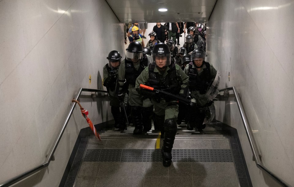  Cops carrying batons walk up the stairs towards demonstrators