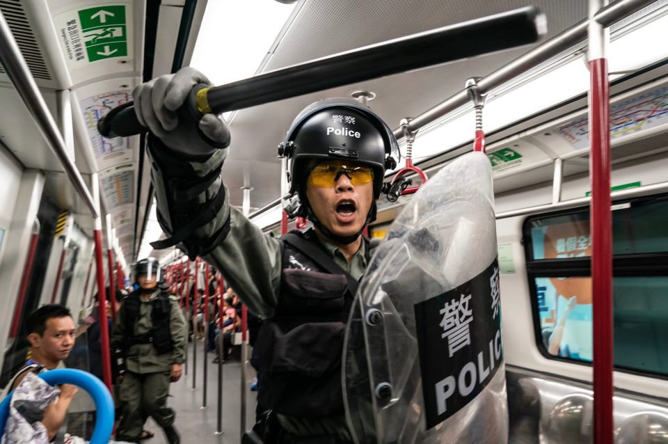  A riot officer brandishes his baton on board a train during the disturbances