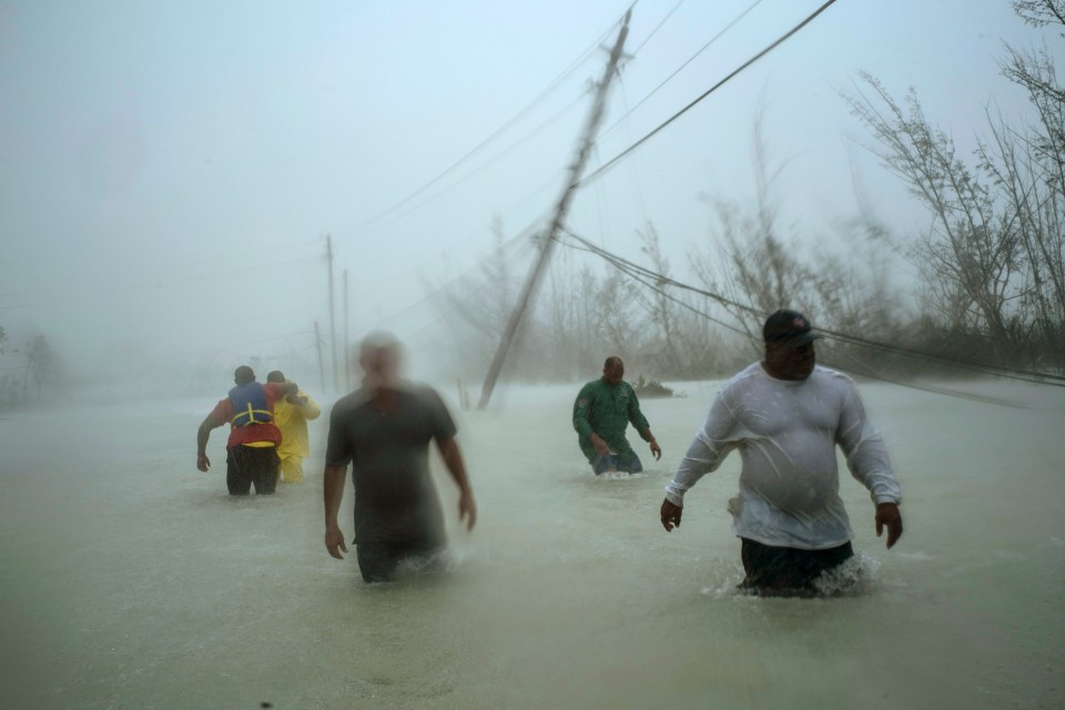  Volunteers wade down a flooded road to rescue families in Freeport, Grand Bahama