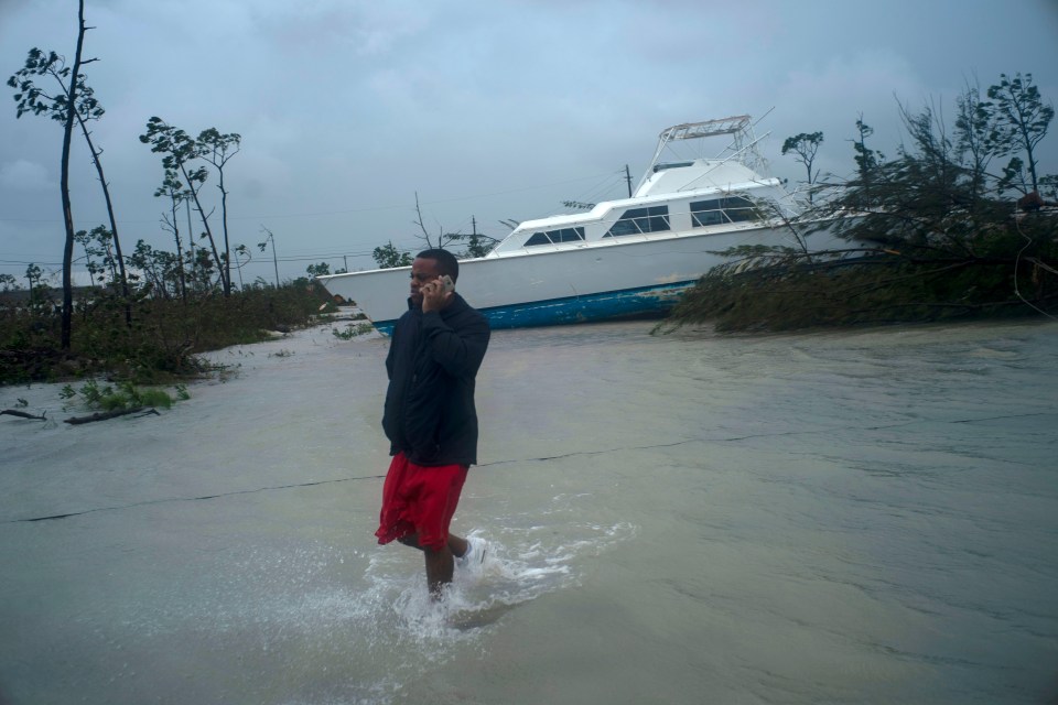  A man talks on his mobile next to a boat thrown onshore by the hurricane in Freeport, Grand Bahama