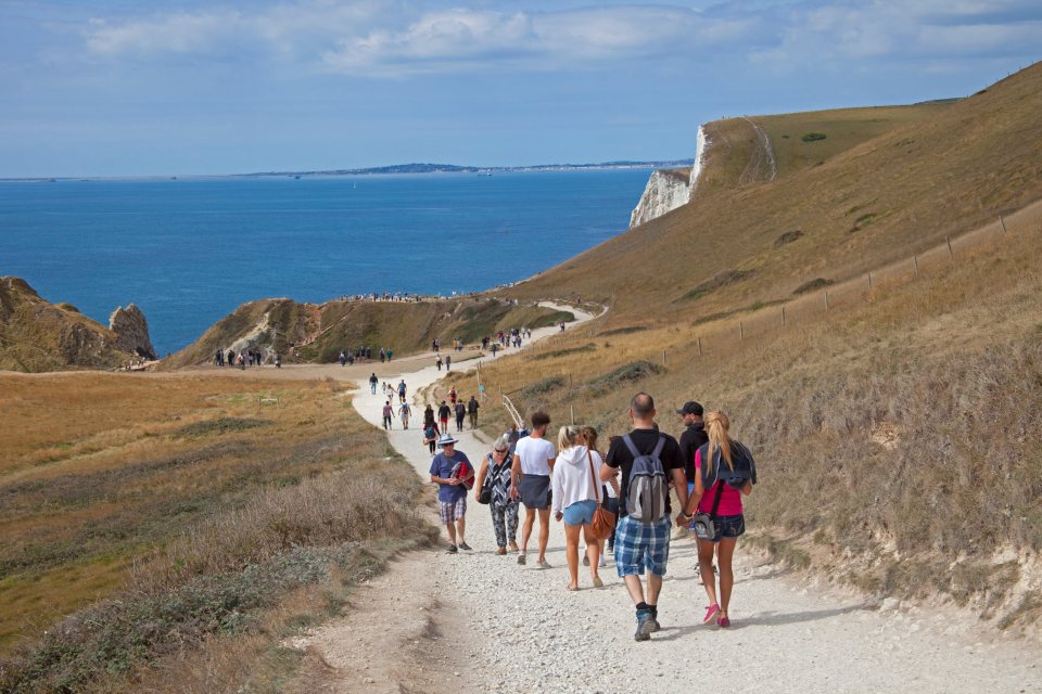  Tourists stroll along a coastal path in Dorset as the warm and sunny weather hits 18C