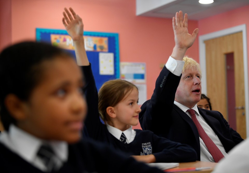  Boris puts his hand up to answer a question as he attends a year four history class with pupils during a visit to Pimlico Primary school in London