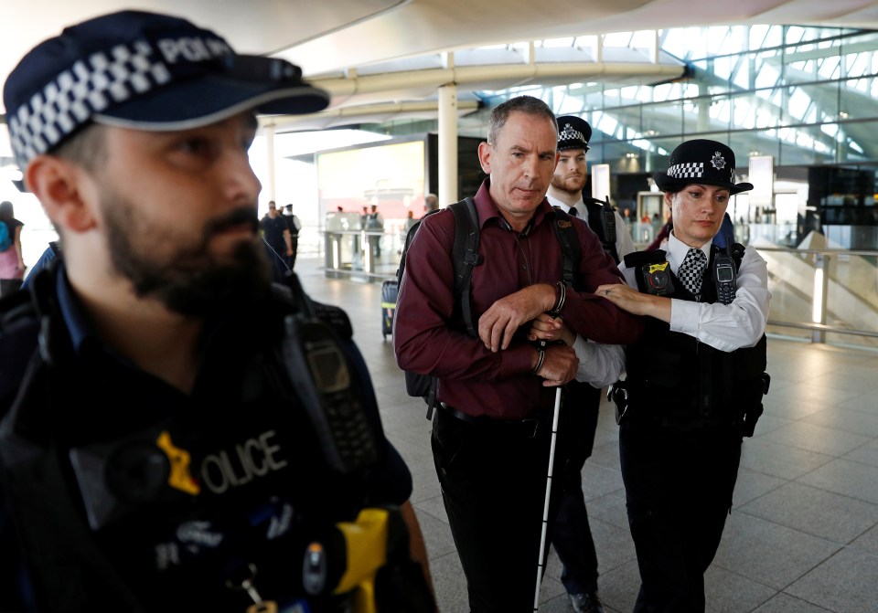 Police officers detain environmental activist James Brown at Heathrow Terminal 2, after climate change protesters tried to launch drones