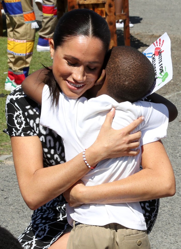  Meghan is embraced by a little boy as they are welcomed to the township