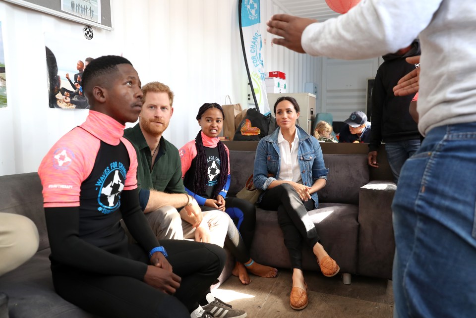  Prince Harry and Meghan Markle sit with some of the surfers during the morning tour of the charity's HQ