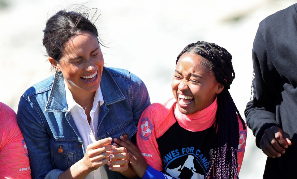  Meghan Markle bursts into laughter as she speaks with one of the young women helped by the charity today