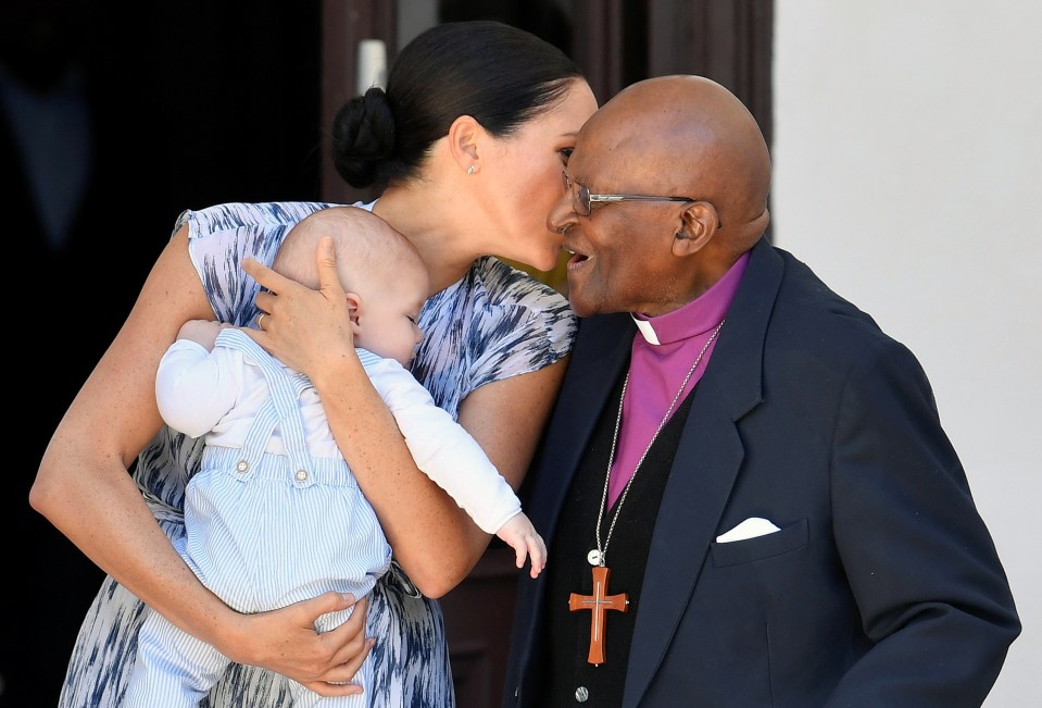  Meghan holds little Archie close as she greets Archbishop Tutu