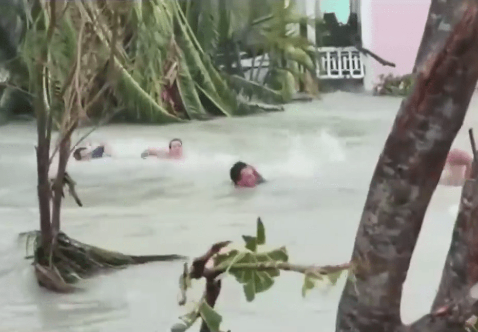  A family desperately swim as they are carried along by raging flood waters