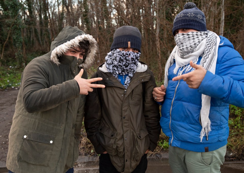  Three Iranian migrants pose at a camp in Calais, France