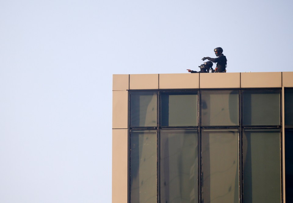  Police officers take position on top of a building during protests on National Day