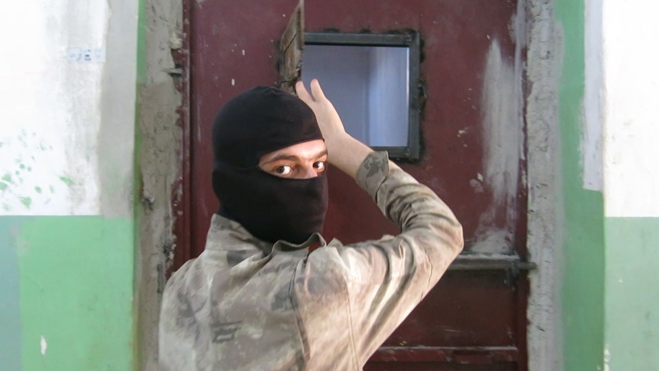  A masked Kurdish guard checks on one of the cells full of ISIS fighters