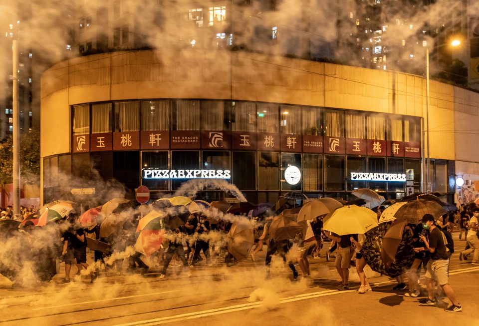  Cops fire tear gas as thousands of protesters with umbrellas fill the streets