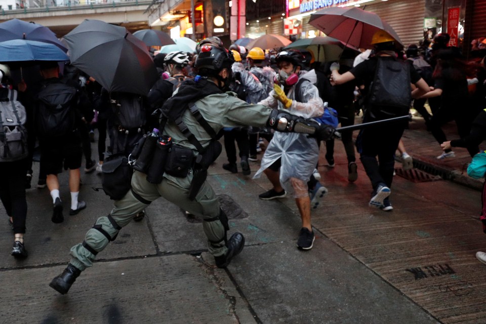  A cop lashes out at protesters with his baton during clashes