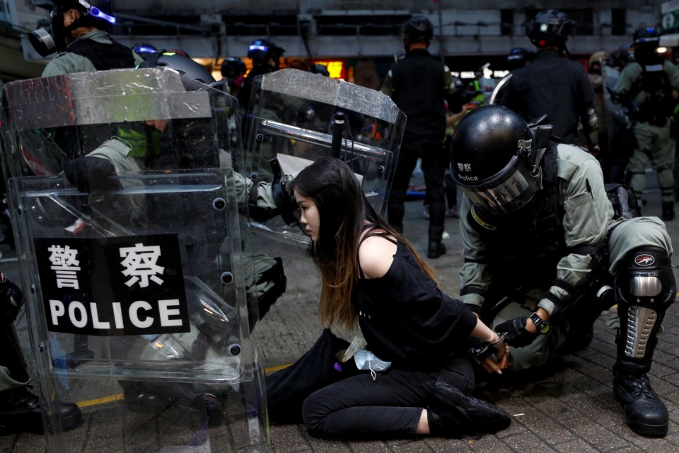  A young woman kneels after being caught by riot cops