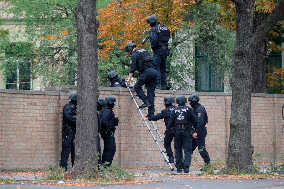 Armed cops scale a wall near the synagogue