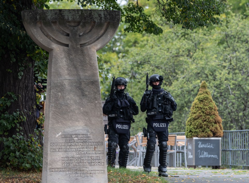 Policemen stand armed behind a monument near the synagogue