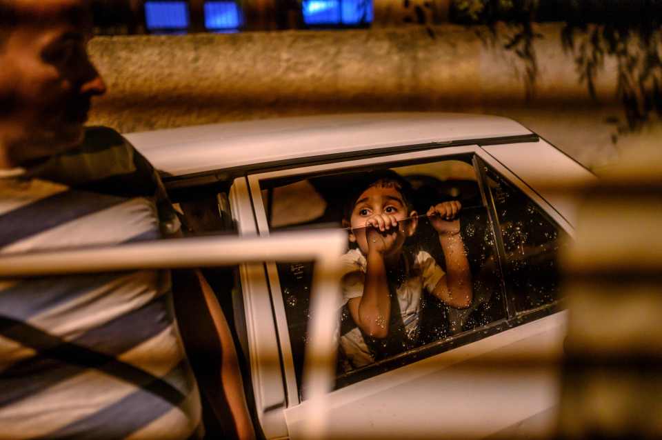  A boy looks from a car as his family prepare to flee after a mortar destroyed part of their home in Akcakale