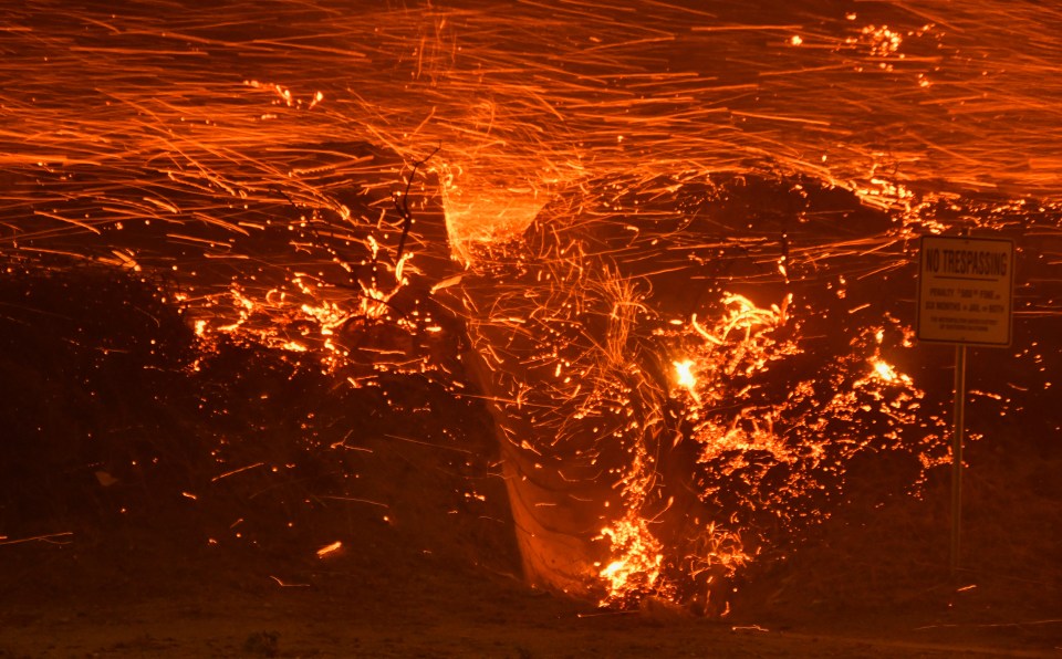 Flying embers cross over the hill sides from a wind-driven wildfire in Sylmar