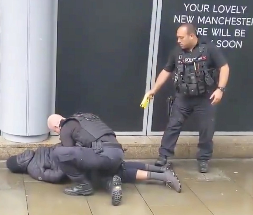  Police officers detain a man outside Manchester's Arndale centre