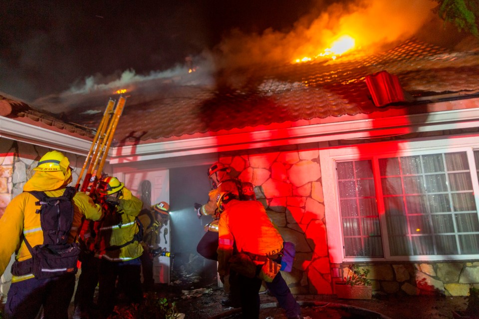 Firefighters enter a burned house as the Saddleridge Fire grows to thousands of acres in just a few hours