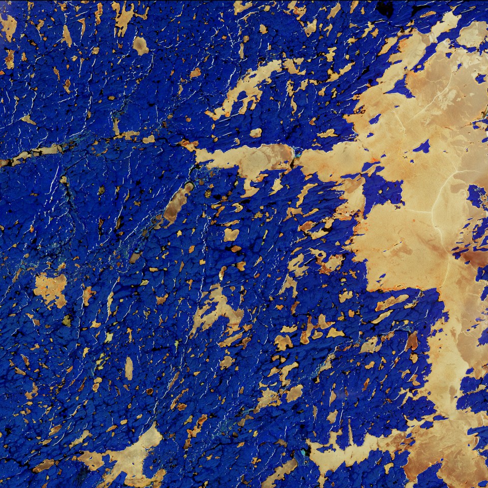  The copper colour in this infrared combination is the presence of lake ice in the Northwest Territories in northern Canada. The lake on the right side is Whitefish Lake, in a region with numerous glacial landforms. Bright wrinkle-like lines are eskers, ridges made of sand and gravel formed by glacial sediments deposited by meltwater rivers flowing on the ice. The blue colour is land dominated by shrub tundra with some spruce stands.