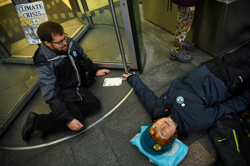  A protester lies on the ground after she glued herself to revolving door of Barclays Bank in Canary Wharf