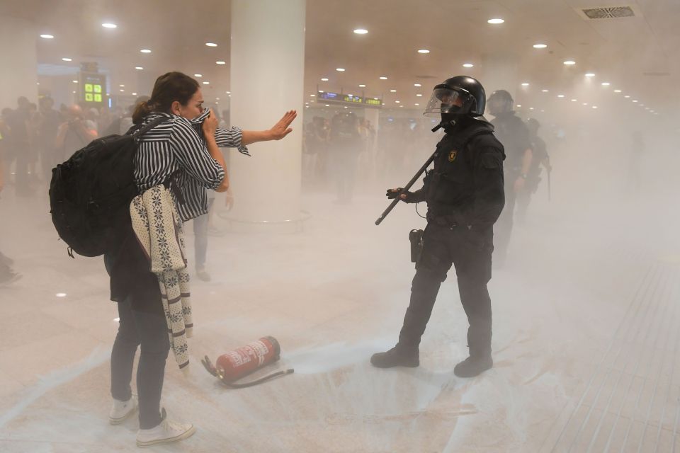  A woman covers her mouth as tear gas fills part of the airport during clashes with riot police yesterday