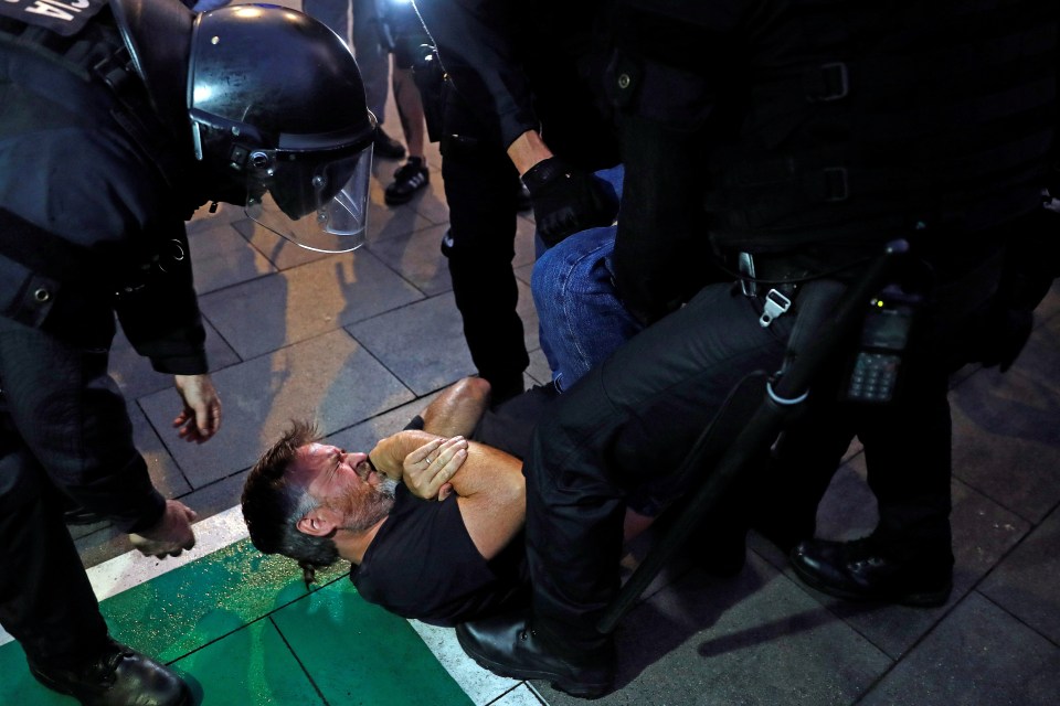  Riot police pin down a pro-Catalonia demonstrator during violent clashes at Barcelona airport on Monday