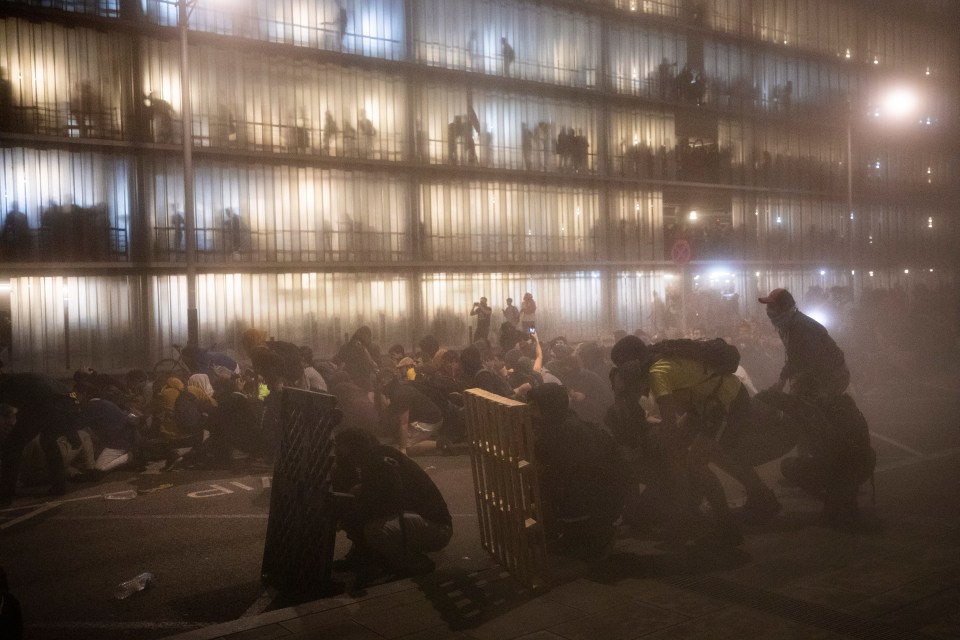  Demonstrators take shelter from riot police firing rubber bullets