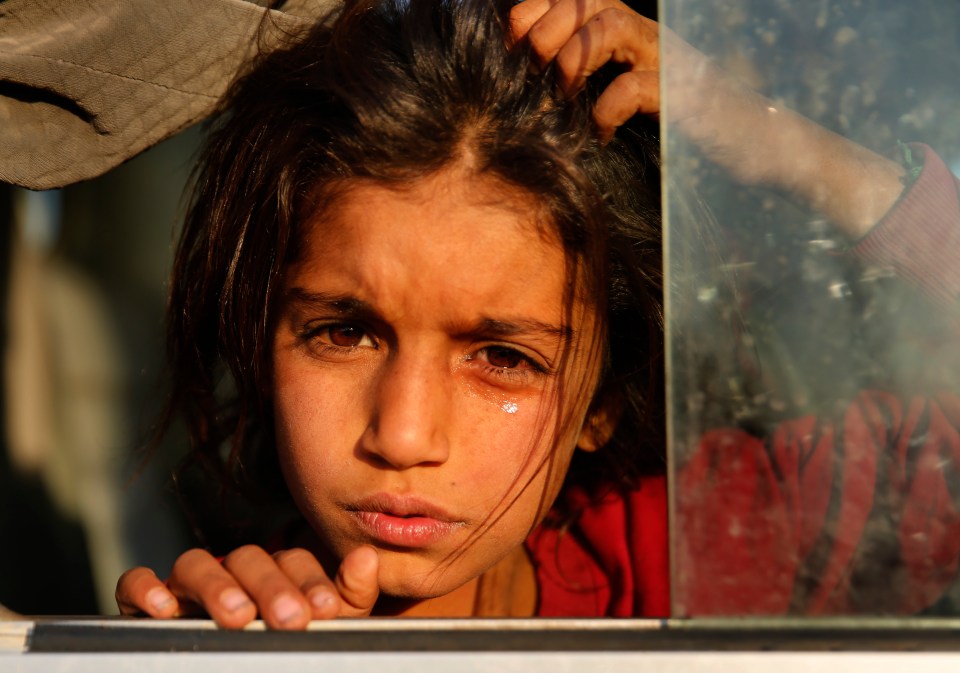  A Syrian girl displaced by the Turkish military operation weeps in a bus upon her arrival at the Bardarash camp, north of Mosul, Iraq