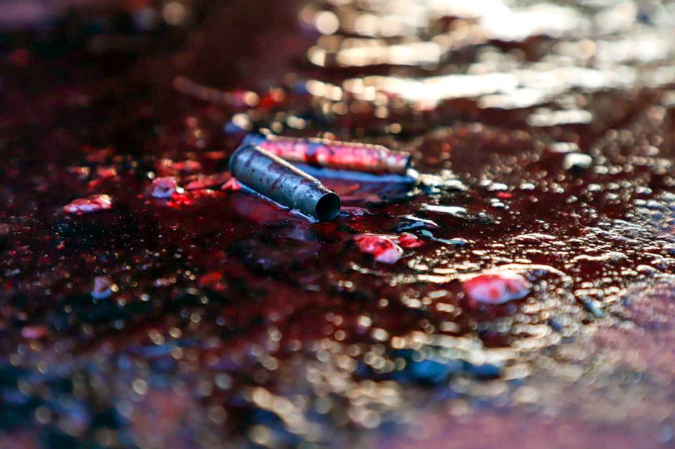 Ammunition shells lay in a pool of blood in the street