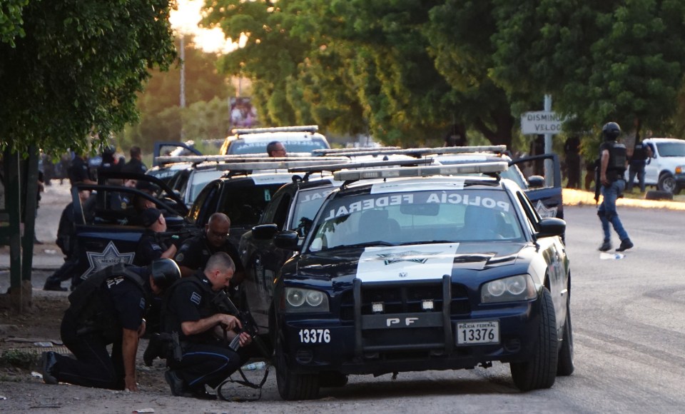 Police take cover behind patrol cars during the shootout