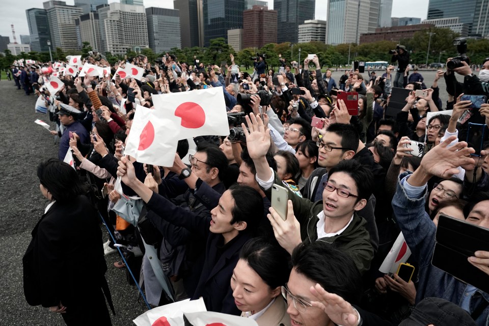 People wave to the motorcade outside the Imperial Palace after the enthronement ceremony