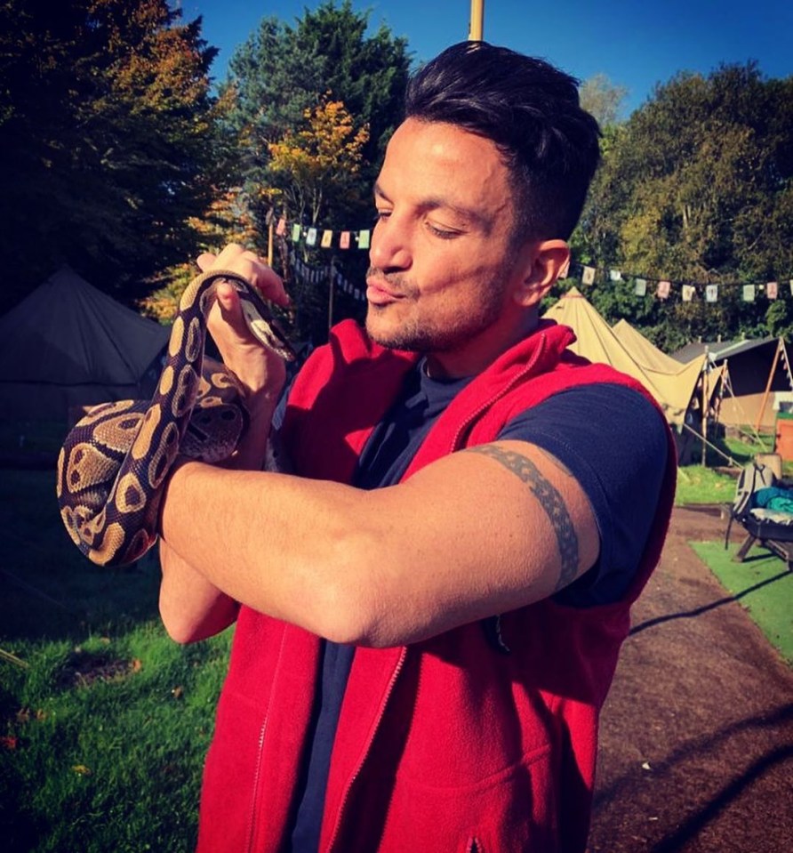 a man in a red vest is holding a snake