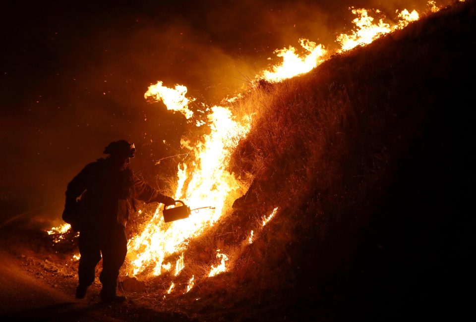  Firefighters use a drip torch to light a back fire