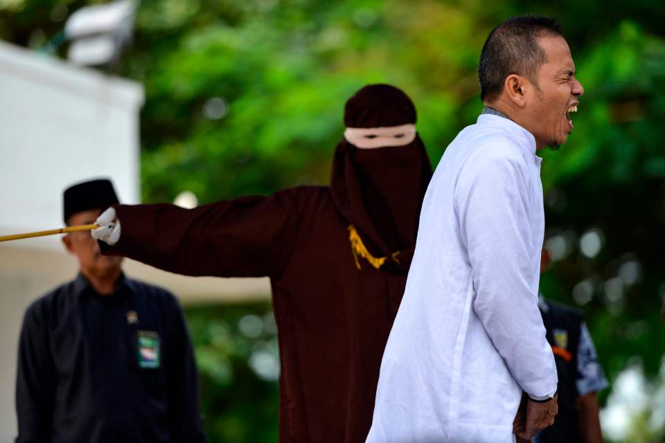  Aceh Ulema Council (MPU) member Mukhlis reacts as he is whipped in public after being accused of having an extramarital affair