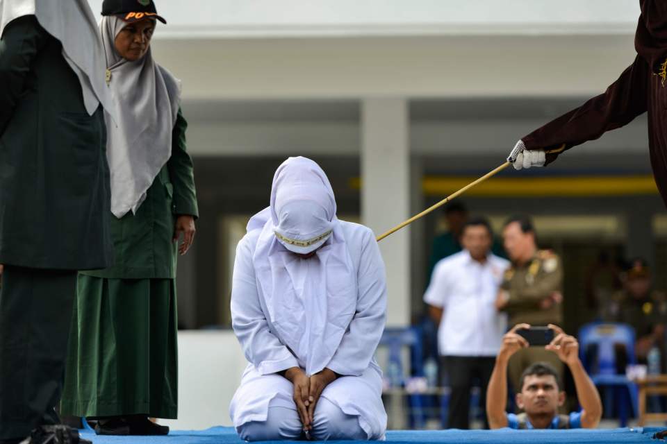  A woman is also whipped in public by a member of the Sharia police in Banda Aceh