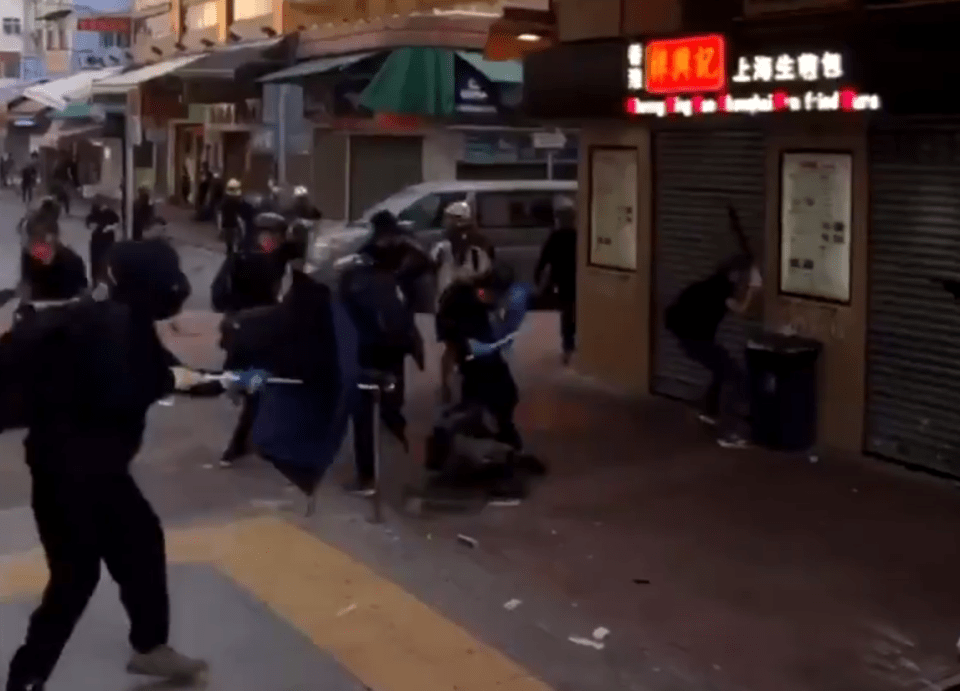  The protester falls to the ground, and others surround him, trying to drag him away