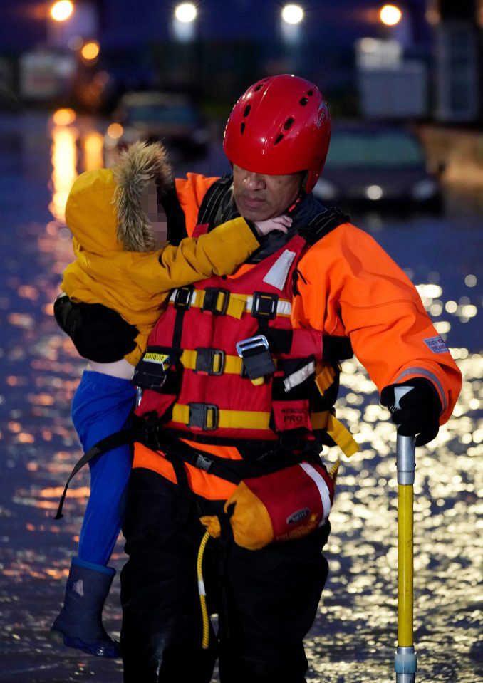  A young child is carried to safety by a fire and rescue worker