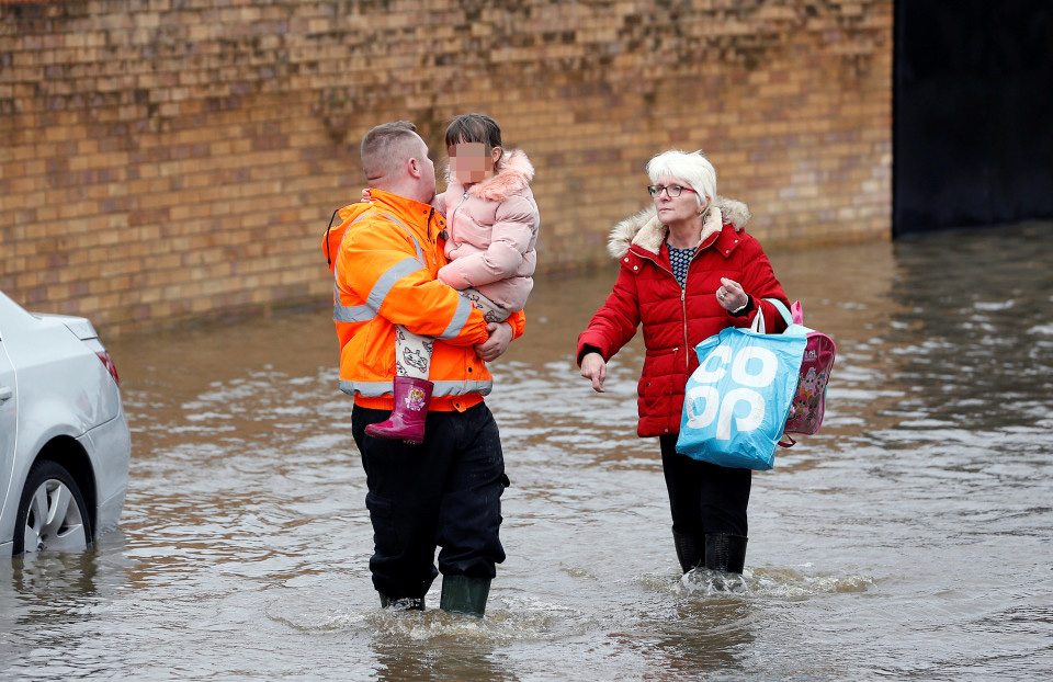  People wade through the submerged streets as they flee their homes