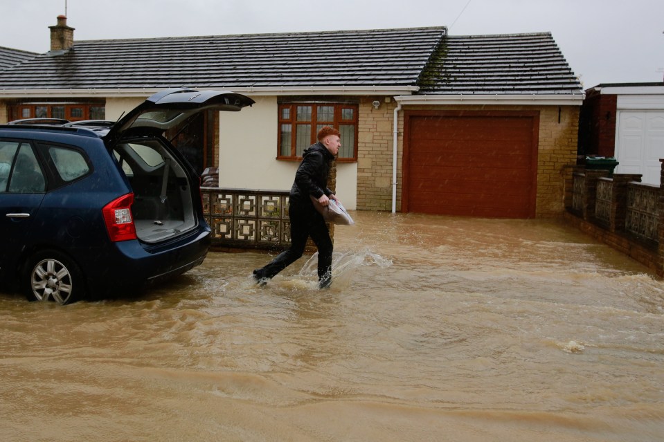  A resident tries to save his home in Whiston from being flooded with sandbags