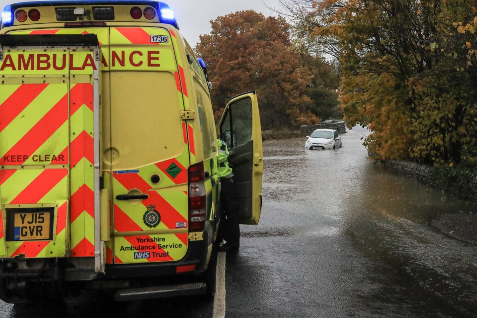  An ambulance stops to help rescue occupants of a white Ford Fiesta as it gets stranded in flood water in Penistone, Barnsley