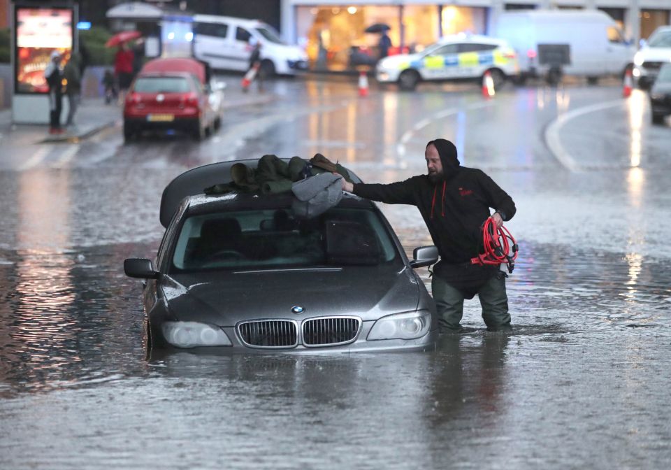  A man abandons his car in a flooded street in Sheffield