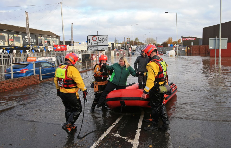  Rescuers help a woman get off an inflatable raft after ferrying her through floodwater