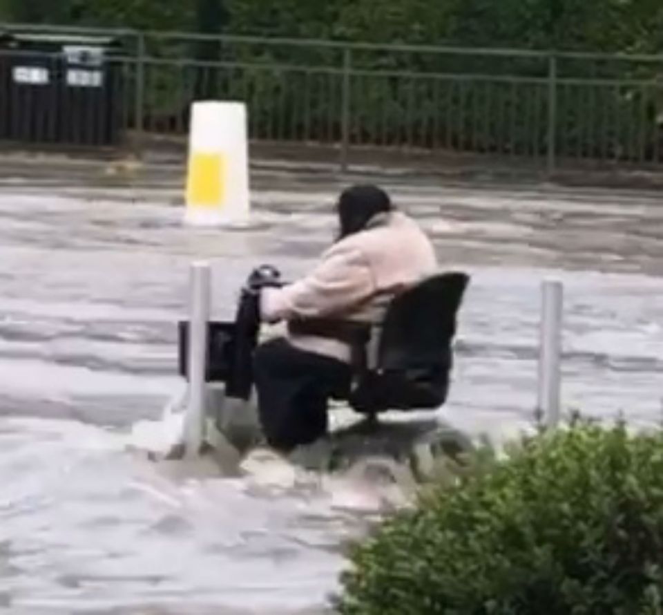  An elderly lady powers her way through the flood water on her mobility scooter in Sheffield