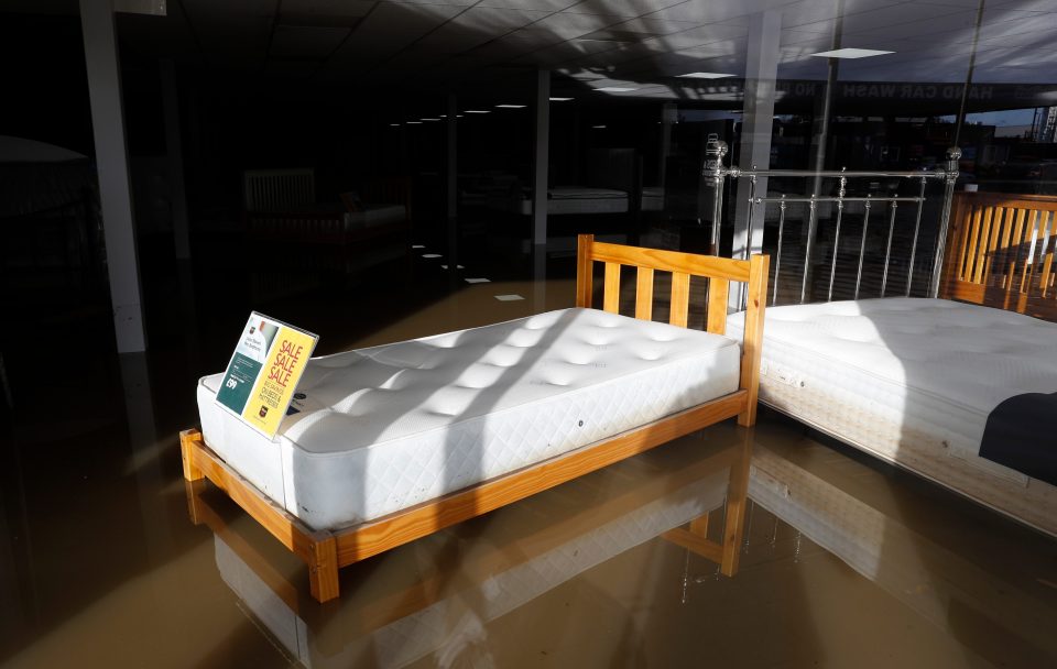  A bed in the window of a shop stands in flood waters after the River Don burst its banks