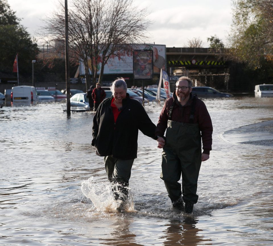  A couple holds hands while walking through floodwater