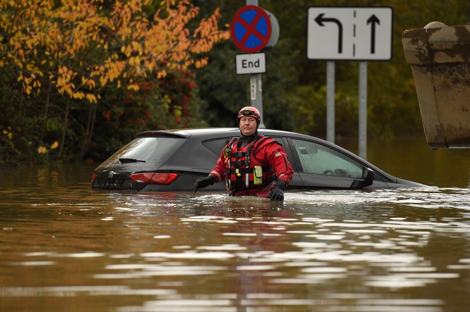  A rescuer wades through the water near an abandoned car